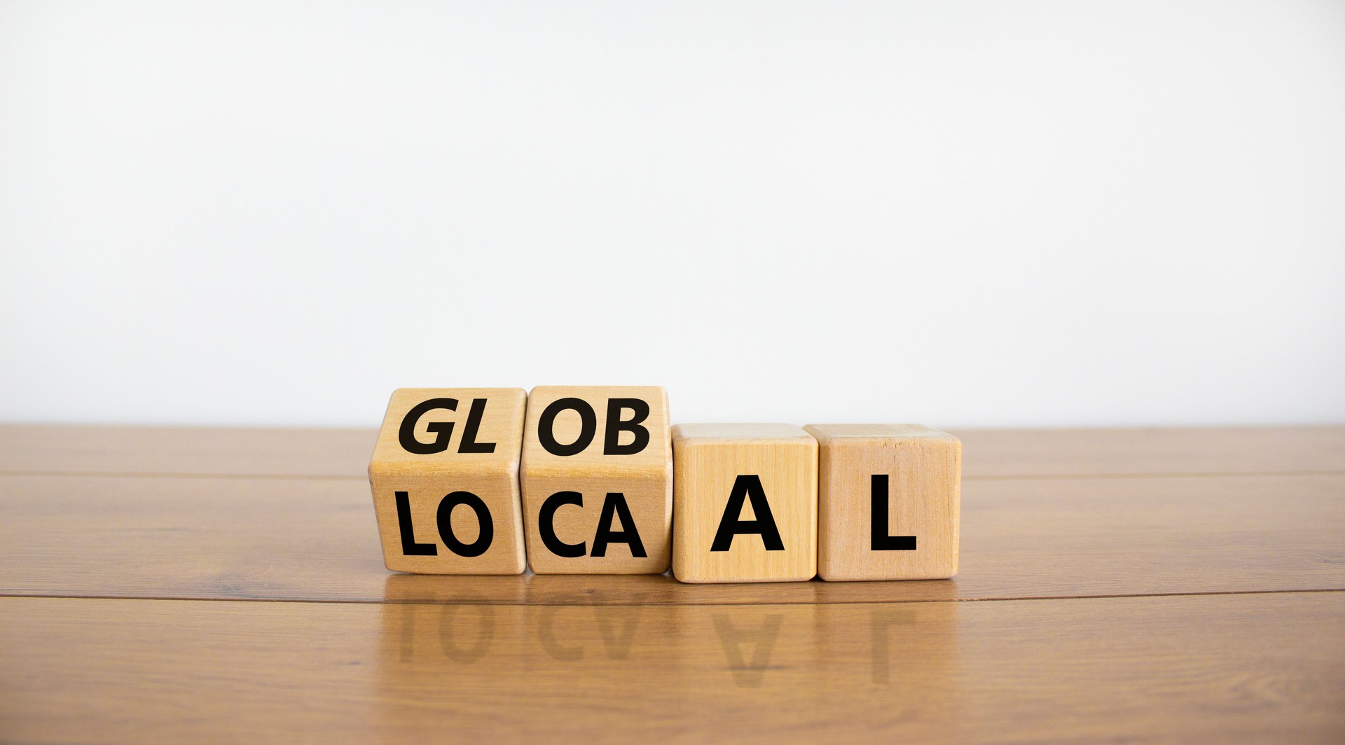 Local or global symbol. Turned wooden cubes and changed the word 'local' to 'global'. Beautiful wooden table, white background. Business and local or global concept. Copy space.